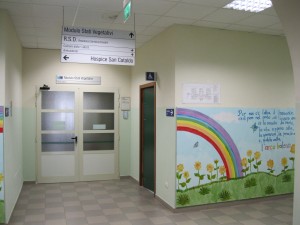 Uno scorcio interno di Hospice San Cataldo dal quale si vede una parete con un arcobaleno dipinto